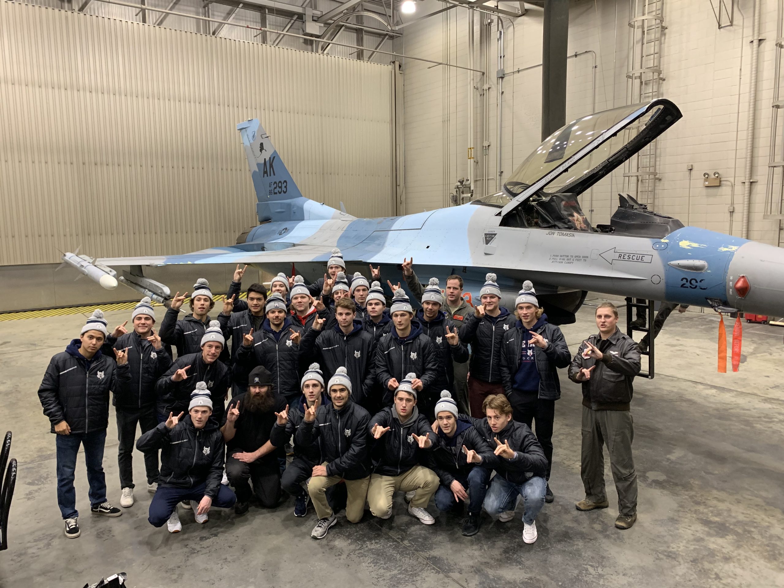 Ice Dogs pose in front of F-16 fighter jet.